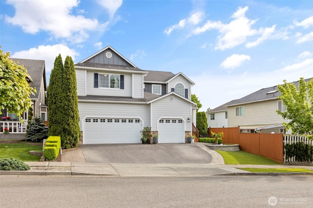 traditional-style home featuring board and batten siding, fence, concrete driveway, stone siding, and a garage