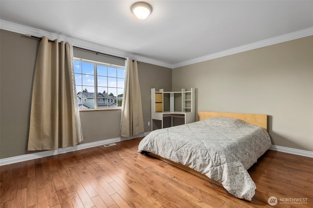 bedroom featuring baseboards, wood-type flooring, and ornamental molding