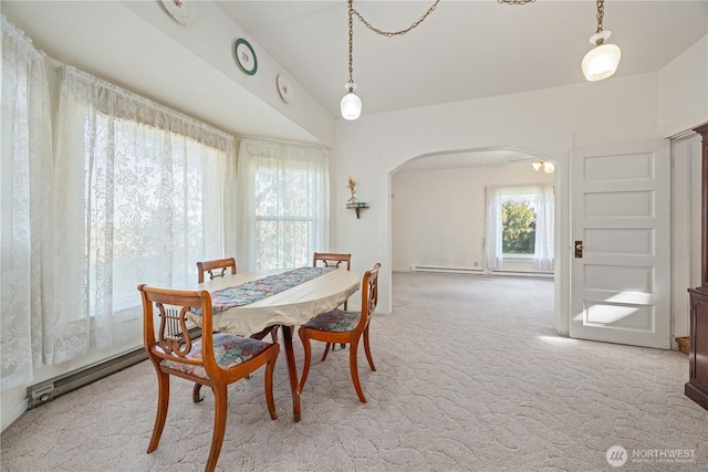 dining area featuring arched walkways, baseboard heating, and light colored carpet
