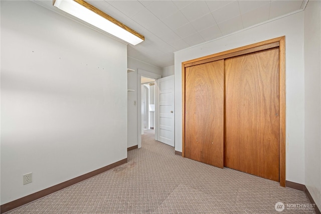 unfurnished bedroom with carpet floors, a closet, and baseboards