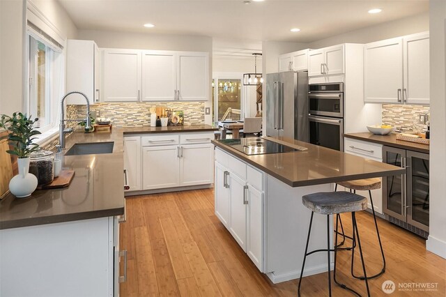 12920 SE 409th Ave, North Bend, WA 98045 - kitchen with stainless steel appliances, dark countertops, a sink, backsplash, and white cabinets