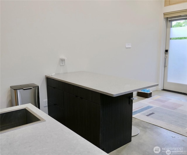 kitchen with light countertops, modern cabinets, a sink, and dark cabinets