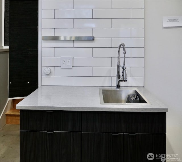 kitchen featuring backsplash, a sink, and light stone countertops