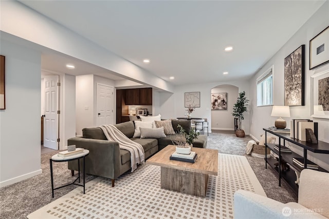 living room featuring light carpet, baseboards, recessed lighting, and arched walkways