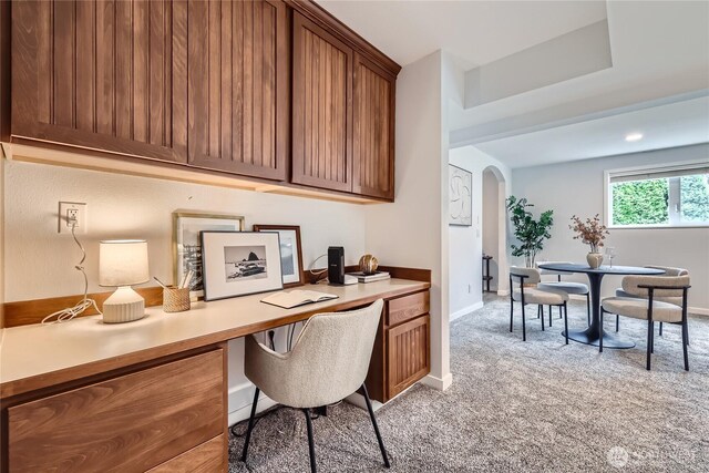 office area with light carpet, built in study area, arched walkways, and baseboards