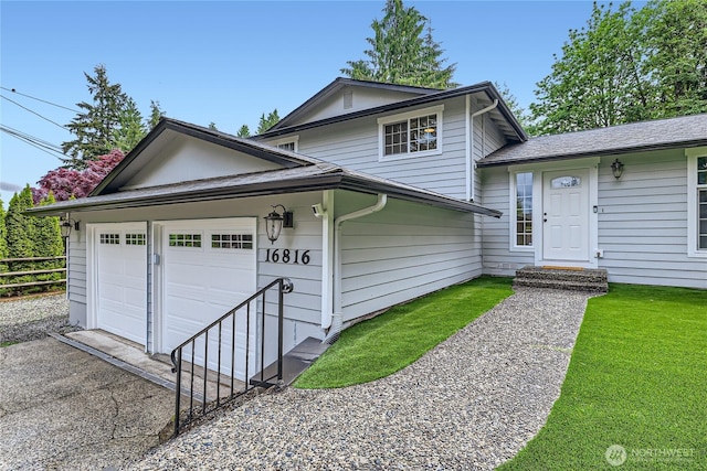 tri-level home featuring asphalt driveway, an attached garage, and fence