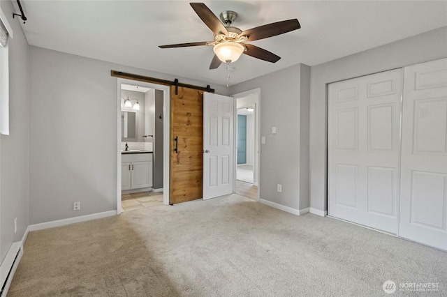 unfurnished bedroom with a baseboard radiator, light colored carpet, a barn door, a closet, and baseboards