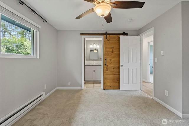 unfurnished bedroom with a baseboard heating unit, carpet flooring, baseboards, and a barn door