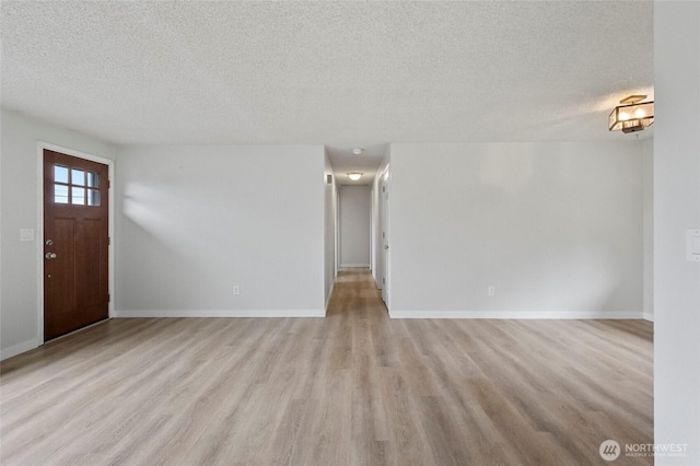 foyer entrance with a textured ceiling, light wood-style floors, and baseboards
