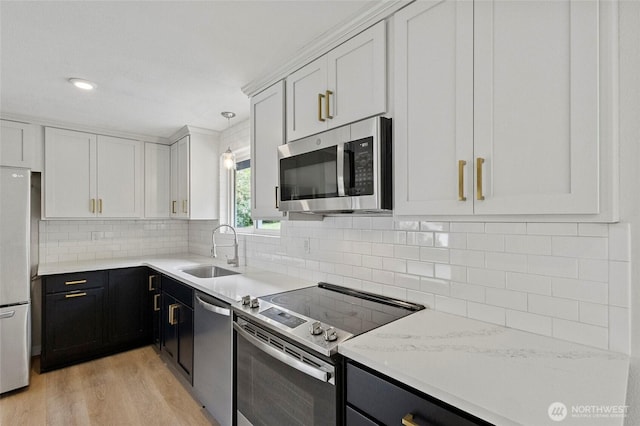 kitchen featuring stainless steel appliances, a sink, light countertops, light wood-style floors, and white cabinetry
