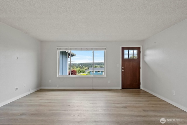 entrance foyer featuring a textured ceiling, light wood-style floors, and baseboards