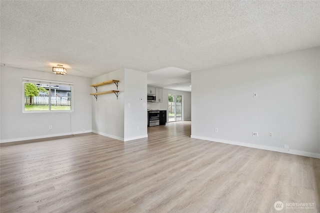 unfurnished living room featuring light wood finished floors, a textured ceiling, and baseboards