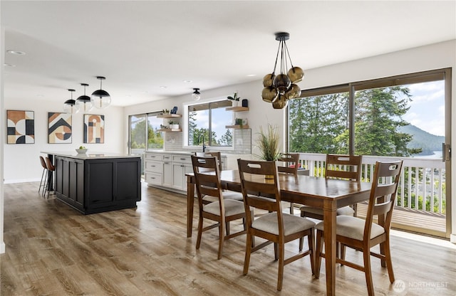 dining space with a chandelier, light wood-type flooring, a mountain view, and recessed lighting