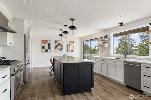 kitchen with appliances with stainless steel finishes, a sink, tasteful backsplash, under cabinet range hood, and white cabinetry