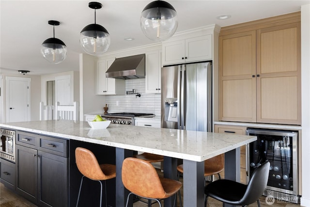 kitchen featuring wall chimney exhaust hood, beverage cooler, appliances with stainless steel finishes, decorative backsplash, and hanging light fixtures