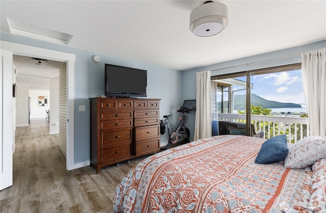 bedroom featuring attic access, access to exterior, wood finished floors, and baseboards