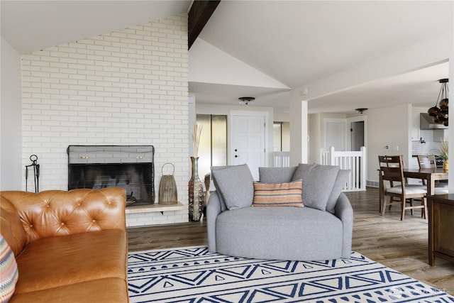 living room with wood finished floors, high vaulted ceiling, beam ceiling, and a brick fireplace