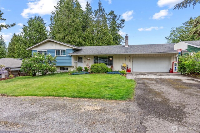 split level home with an attached garage, asphalt driveway, a chimney, a front lawn, and a shingled roof