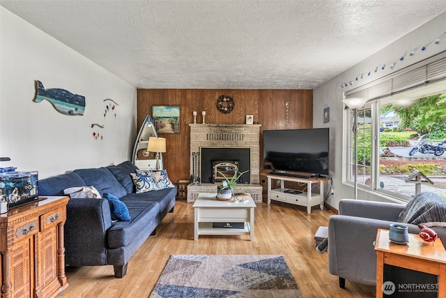living room with a textured ceiling, light wood finished floors, and a brick fireplace