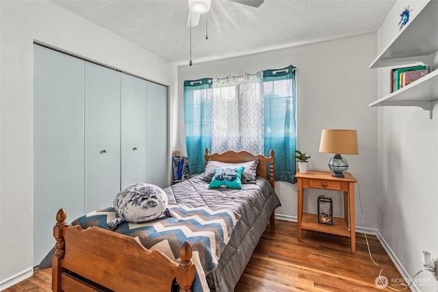 bedroom featuring wood finished floors, a closet, a ceiling fan, and baseboards