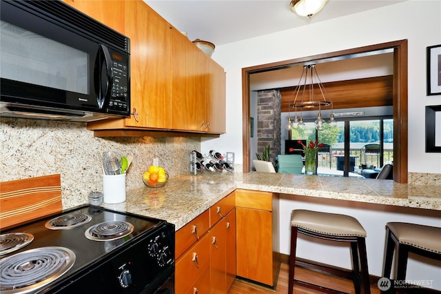 10 Olympic Pl Unit 10, Port Ludlow, WA 98365 - kitchen with black appliances, backsplash, tile counters, brown cabinetry, and wood finished floors