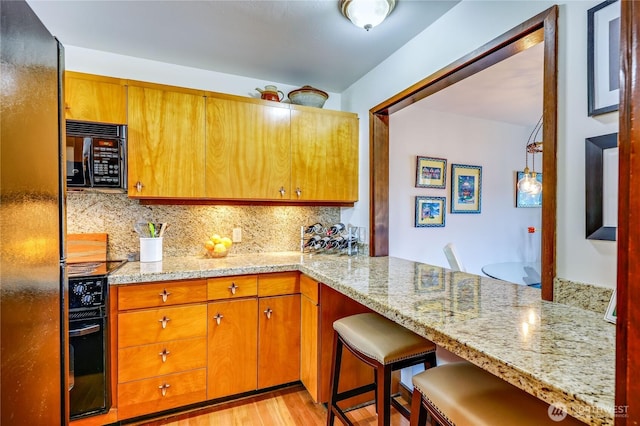 10 Olympic Pl Unit 10, Port Ludlow, WA 98365 - kitchen featuring black microwave, light wood finished floors, backsplash, a breakfast bar, and freestanding refrigerator