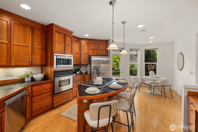 27424 NE 147th Ct, Duvall, WA 98019 - kitchen featuring appliances with stainless steel finishes, dark countertops, recessed lighting, a breakfast bar area, and light wood finished floors