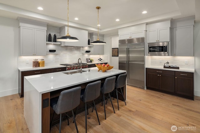 3976 154th Ave SE, Bellevue, WA 98006 - kitchen with built in appliances, decorative backsplash, light countertops, a sink, and light wood finished floors