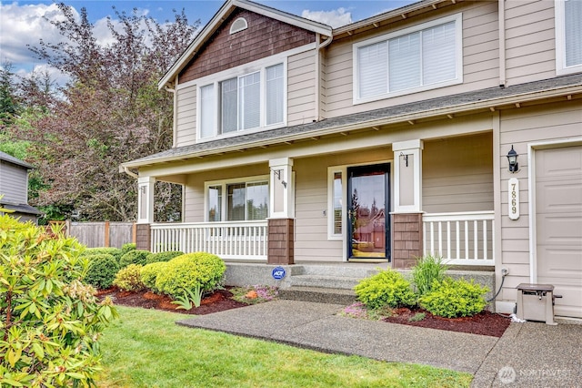 view of front of home featuring covered porch, fence, and a garage