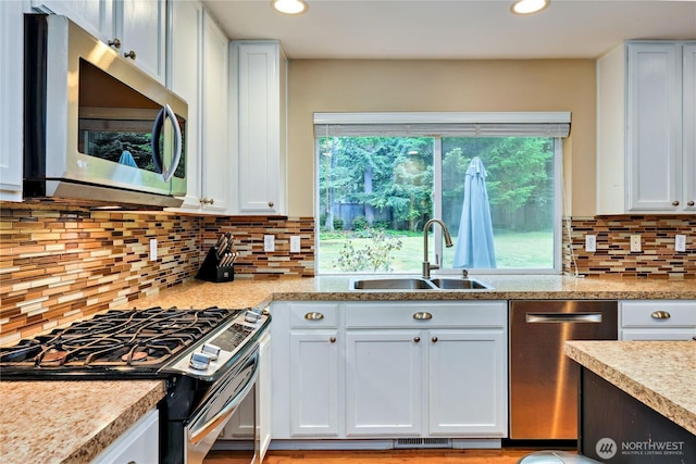 kitchen featuring appliances with stainless steel finishes, a sink, light countertops, tasteful backsplash, and white cabinetry