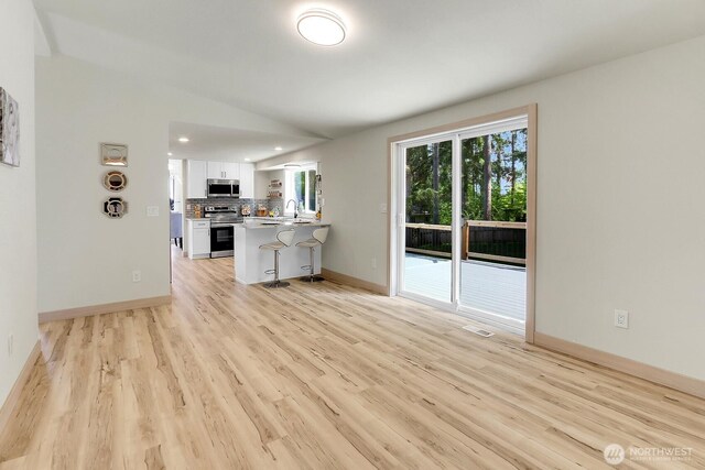 9630 SE Driftwood Dr, Port Orchard, WA 98367 - unfurnished living room featuring light wood-style flooring, lofted ceiling, a sink, baseboards, and recessed lighting