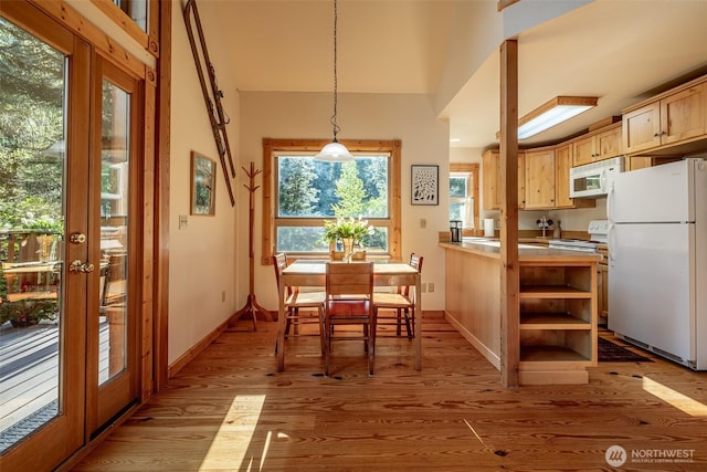 dining area with light wood-type flooring, french doors, and baseboards
