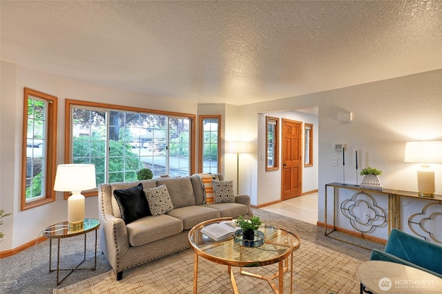 living area featuring healthy amount of natural light, a textured ceiling, baseboards, and light carpet