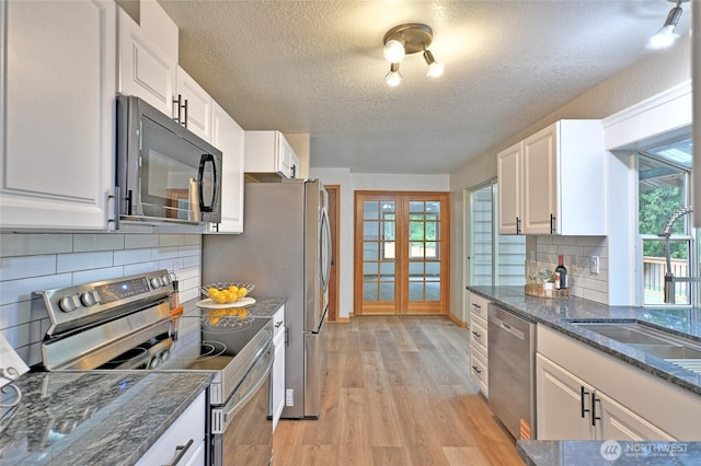 kitchen featuring stainless steel appliances, a textured ceiling, light wood finished floors, white cabinetry, and french doors