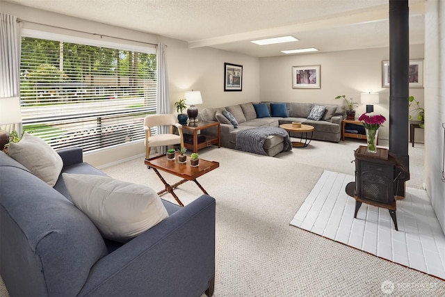carpeted living room featuring a wood stove and a textured ceiling