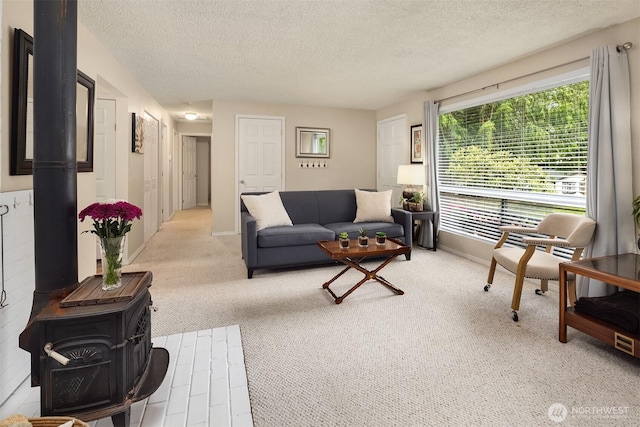 carpeted living room with a wood stove, a textured ceiling, and baseboards