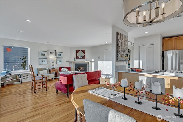 dining area with recessed lighting, light wood-type flooring, a chandelier, and a fireplace