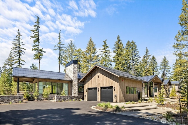 1501 Kokanee Loop, Cle Elum, WA 98922 - view of front facade featuring an attached garage, a chimney, asphalt driveway, metal roof, and stone siding