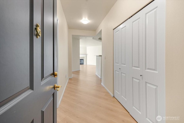 hallway with light wood-type flooring and baseboards