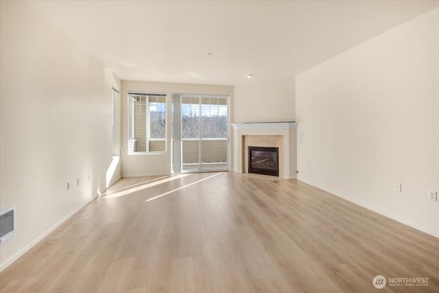 unfurnished living room with light wood-style floors, a fireplace, and baseboards