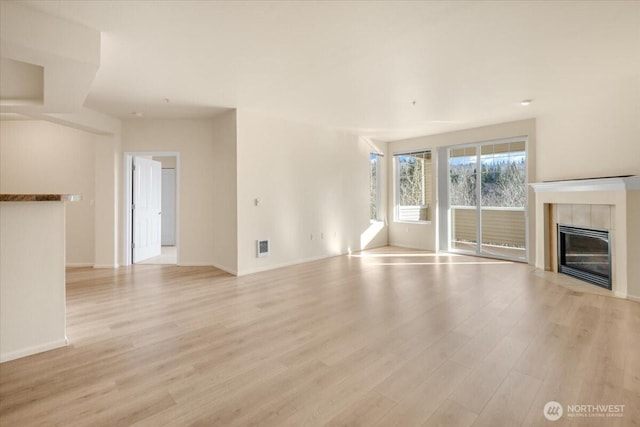 unfurnished living room featuring light wood-style flooring, a fireplace, and baseboards