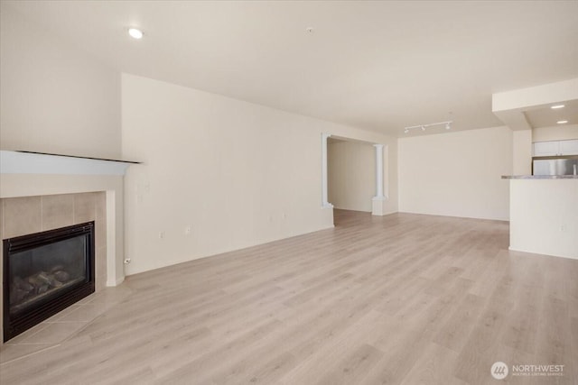 unfurnished living room with a tile fireplace, light wood-style flooring, and recessed lighting