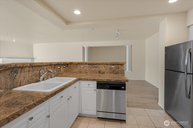 kitchen featuring stainless steel appliances, a sink, white cabinetry, decorative backsplash, and light tile patterned flooring