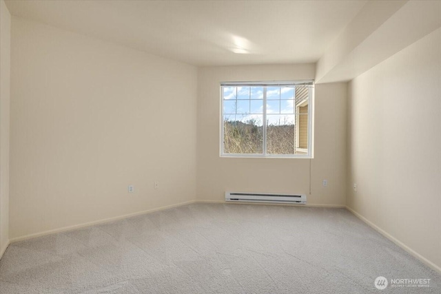 carpeted spare room featuring a baseboard radiator and baseboards