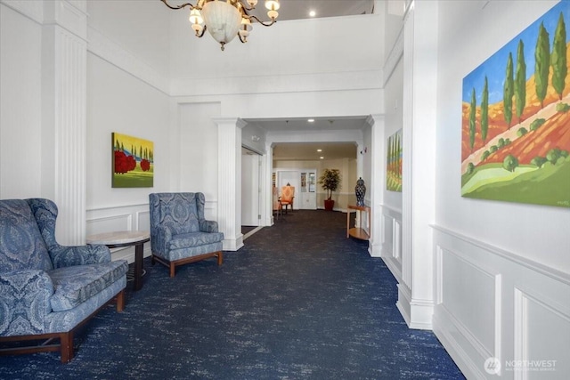 hallway with a chandelier, a decorative wall, carpet floors, and a wainscoted wall