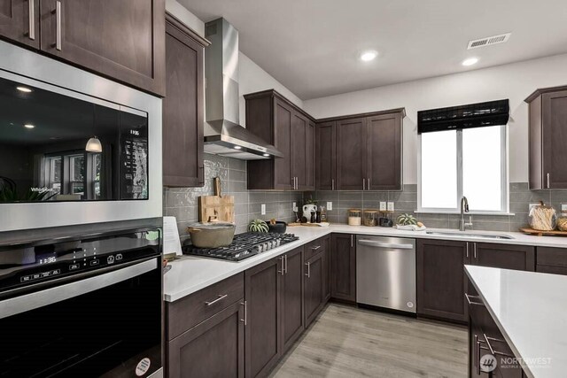 11434 SE 84th St Unit 34, Newcastle, WA 98056 - kitchen featuring appliances with stainless steel finishes, wall chimney exhaust hood, a sink, dark brown cabinets, and light countertops