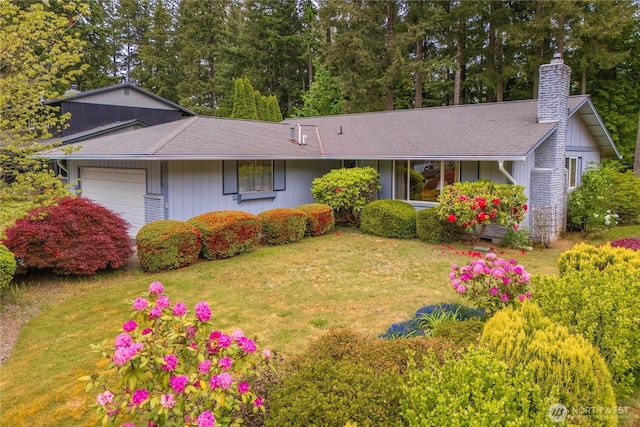 ranch-style house with a chimney, an attached garage, a front lawn, and a shingled roof