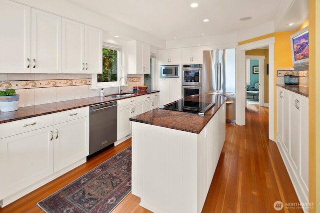 1712 Arch Ave SW, Seattle, WA 98116 - kitchen featuring appliances with stainless steel finishes, a sink, a kitchen island, wood finished floors, and backsplash