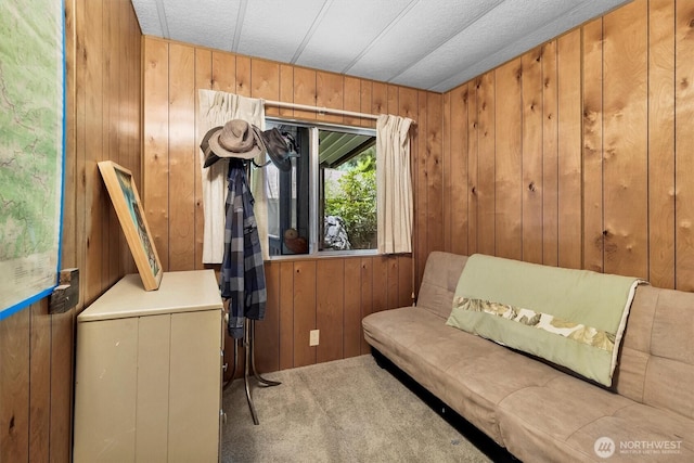 sitting room featuring wood walls and carpet