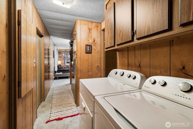 laundry area featuring cabinet space, light colored carpet, washer and dryer, and wooden walls